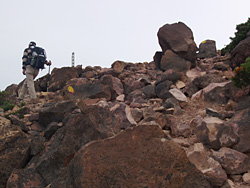 活火山らしい赤茶けた火山礫の道を登る